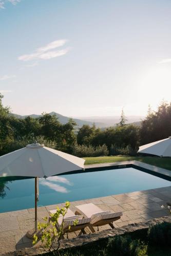 an umbrella and a bench next to a swimming pool at Villa Montanare - romantic escape Tuscany in Cortona