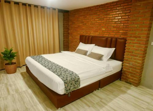 a bedroom with a large bed with a brick wall at BaanBaimai Homestay in Chiang Rai