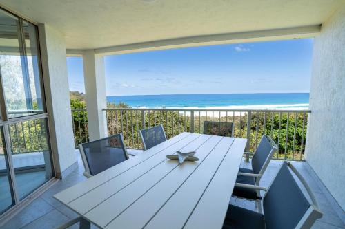 a table and chairs on a balcony with the ocean at Whalewatch Ocean Beach Resort in Point Lookout
