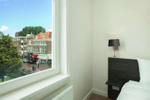 a bedroom with a window with a view of a city at Stayci Serviced Apartments Denneweg in The Hague