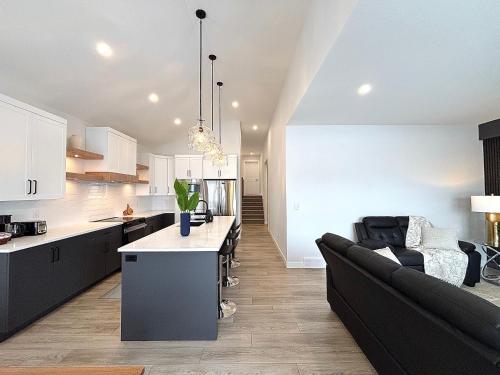 a kitchen and living room with a black couch at Cozy Heaven in Saskatoon