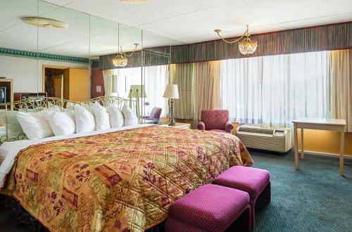 a hotel room with a large bed with purple chairs at Rodeway Inn & Suites in Tupelo