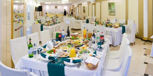 un comedor con mesas blancas y sillas blancas en Hotel Mars, en Leópolis