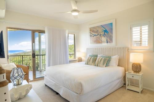 a white bedroom with a bed and a balcony at Whalewatch Ocean Beach Resort in Point Lookout