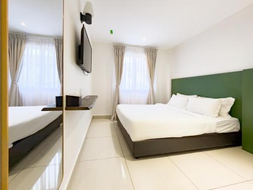 a hotel room with two beds and a television at Living At DSulaiman Hotel in Kuala Lumpur
