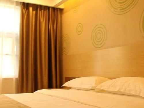 a bedroom with a bed with white pillows and a window at GreenTree Inn Xianning Tongcheng County Bus Station Business Hotel in Tongcheng