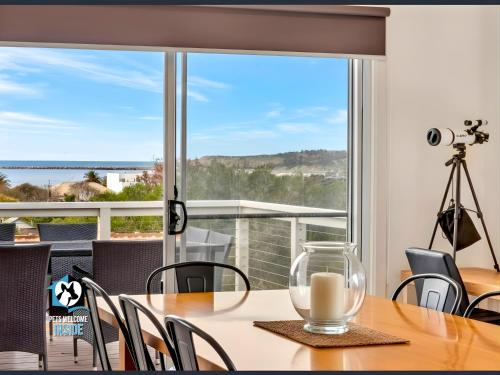 a dining room with a table and a view of the ocean at Modern Coastal with Sparkling Sea Views in Victor Harbor in Victor Harbor