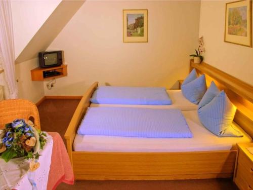 a bedroom with a wooden bed with blue pillows at Gasthaus Hohberg in Durbach