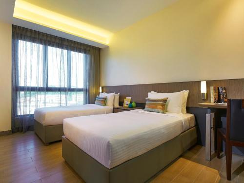 a hotel room with two beds and a window at Oasia Residence Singapore by Far East Hospitality in Singapore