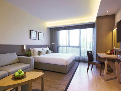 a hotel room with a bed and a couch at Oasia Residence Singapore by Far East Hospitality in Singapore