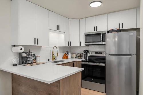 a kitchen with white cabinets and a stainless steel refrigerator at Brand New 2BR Queen Anne Condo Designer's Taste in Seattle