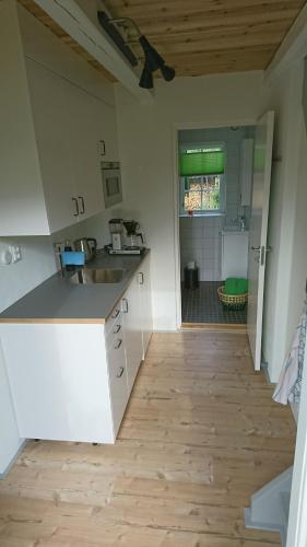 a kitchen with white cabinets and a wooden floor at Lillan in  Torna Hällestad