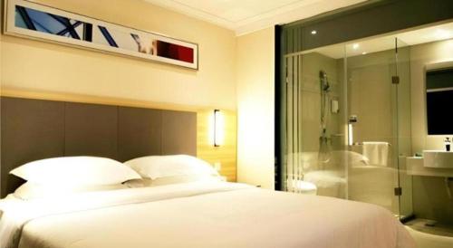 a bedroom with a large white bed and a bathroom at City Comfort Inn Hengyang Jiefang Avenue Business Walking Street in Hengyang