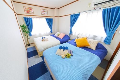 two beds in a small room with blue curtains at Belmont 201 3min to Station Easy Access Ueno Asakusa Skytree Sleeps 5 in Tokyo