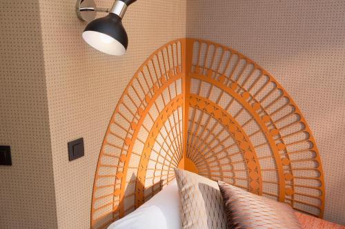a bed with an orange head board in a bedroom at Hotel Espace Champerret in Levallois-Perret