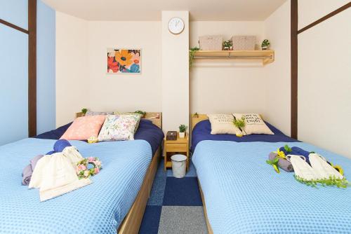 two beds in a small room with blue sheets at Belmont 203 3min to Station Easy Access Ueno Asakusa Skytree Sleeps 4 in Tokyo