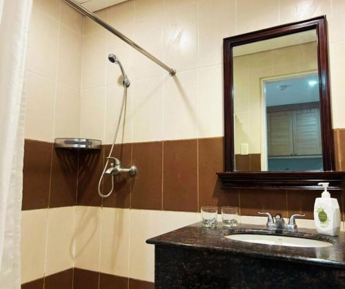 Un baño con lavabo y ducha con espejo. en Crosswinds Standard Suite, en Ulot