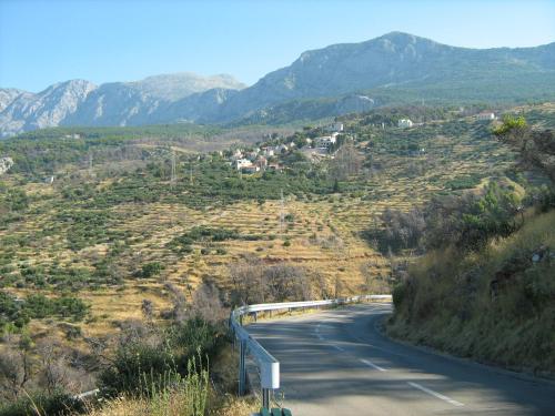 a winding road on a hill with mountains in the background at Adria Apartments in Podgora