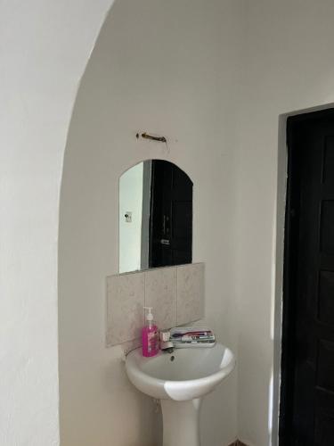 a white bathroom with a sink and a mirror at Raine house in Ukunda