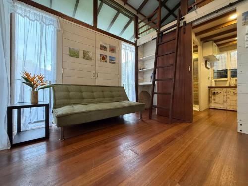 a living room with a green couch and a wooden floor at Rain Tree Country Home in Bukit Mertajam