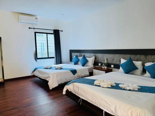 Un dormitorio con dos camas con almohadas azules y blancas. en Real Hostel, en Kaôh Rŭng (3)