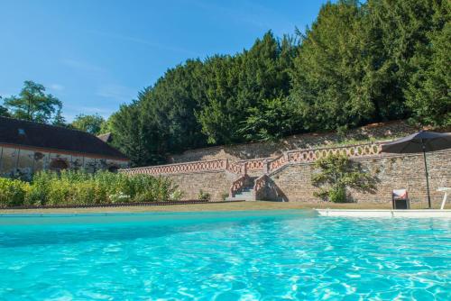 Cahan的住宿－Le Manoir de Bénédicte B&B，一座游泳池,旁边是带雨伞的砖墙