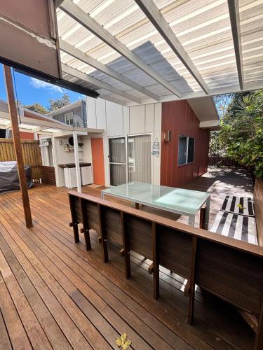 an outdoor patio with a glass table on a wooden deck at Allure Stradbroke Resort in Point Lookout