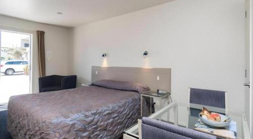 a hotel room with a bed and a glass table at Hawera Central Motor Lodge in Hawera