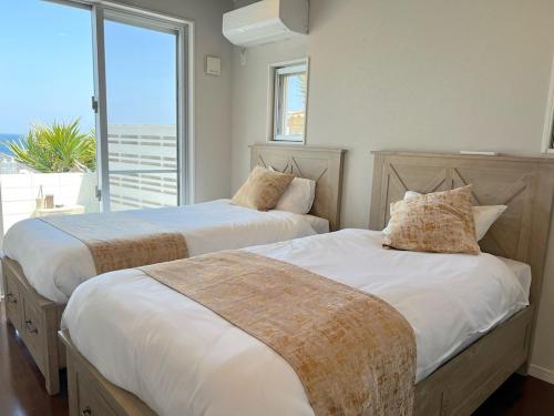 two beds in a room with a large window at 全室オーシャンビュー外階段付き一棟貸切プライベートヴィラ in Kouri