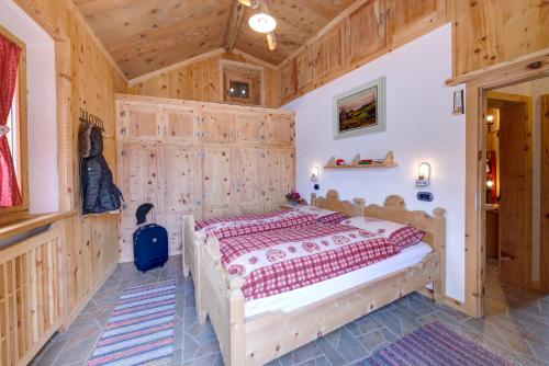 1 dormitorio con 1 cama con pared de madera en Al Beltram, en Livigno