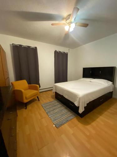 a bedroom with a bed and a ceiling fan and a chair at Simple room in Paterson