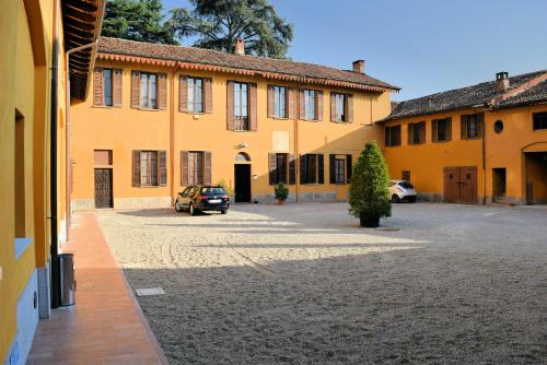 un grand bâtiment jaune avec des voitures garées dans une cour dans l'établissement Corte Certosina, à Trezzano sul Naviglio