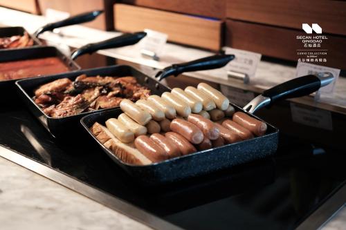 Un buffet de perritos calientes y otras comidas en un mostrador. en Secan Hotel Qingdao, Curio Collection By Hilton, en Qingdao