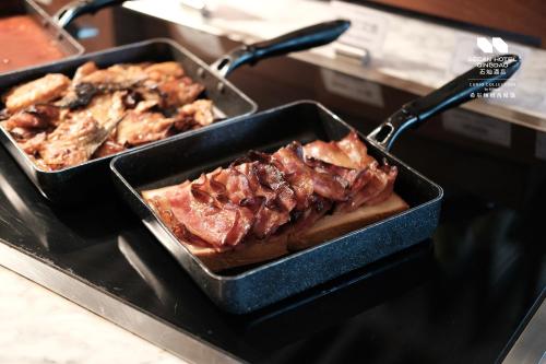 Una sartén con carne y otros alimentos en una estufa en Secan Hotel Qingdao, Curio Collection By Hilton, en Qingdao