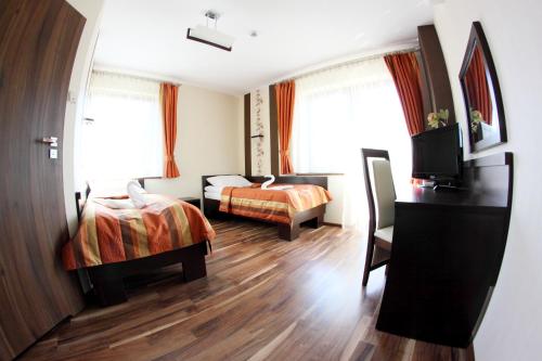 a hotel room with two beds and a desk at Hotel Mieszko in Rzeszów