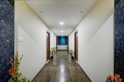 a hallway with white walls and wooden floors and plants at Hotel O PRIME HUB in Lingampalli