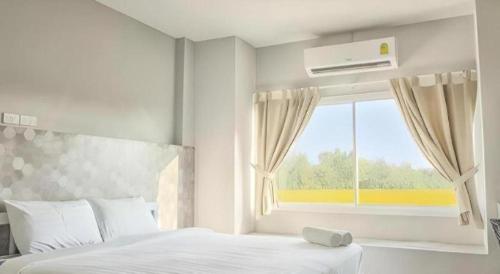 une chambre blanche avec un lit et une fenêtre dans l'établissement Kosit One Hotel, à Ban Bung Sam Phan Nok