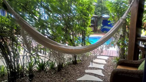 a hammock in a garden with a swimming pool at Pousada DiMari in Boicucanga