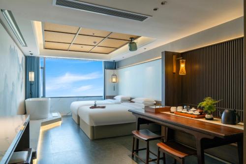 a hotel room with a bed and a desk and a bed and a desk at Dayucang Tea Sea Cloud Inn Jingmai Ancient Tree Tea Forest Store in Mengzhe