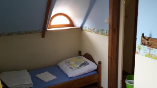 a small bed in a small room with a window at Zagroda Pod Gontem in Kopalino