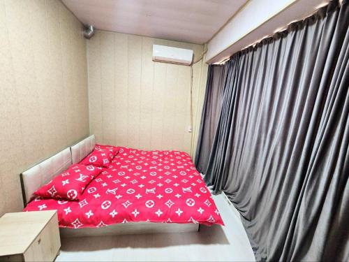 a small room with a red bed and a window at Apartment for 5 persons, in Chilanzar in Tashkent