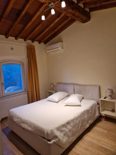 a bedroom with a bed with white sheets and a window at Bed&Breakfast La Zagara in Querceta
