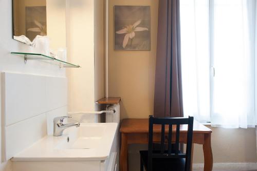 a bathroom with a sink and a chair next to a window at Hôtel des Facultés in Lyon