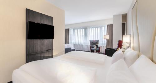 ein Hotelzimmer mit einem großen Bett und einem Fernseher in der Unterkunft PLAZA INN Mannheim in Mannheim