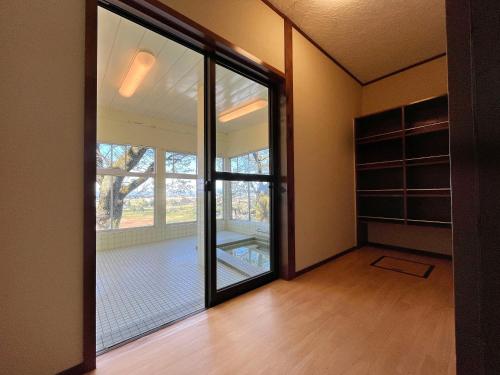 una habitación vacía con una gran puerta corredera de cristal en 眺望の湯宿弁天, en Tonami