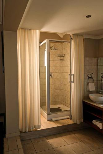 a bathroom with a shower and a sink at Pemabwe Guest Lodge in Harare