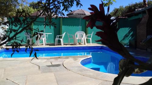 une piscine avec des chaises blanches et un mur végétal dans l'établissement Pousada Reis, à Pirenópolis