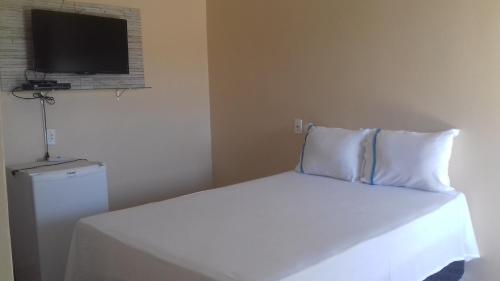 une chambre avec un lit blanc et une télévision dans l'établissement Pousada Reis, à Pirenópolis