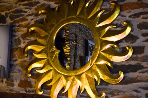 a gold sunburst mirror on a stone wall at Le Café du Village - Bar à cocktails & à Ambiance in Lohéac