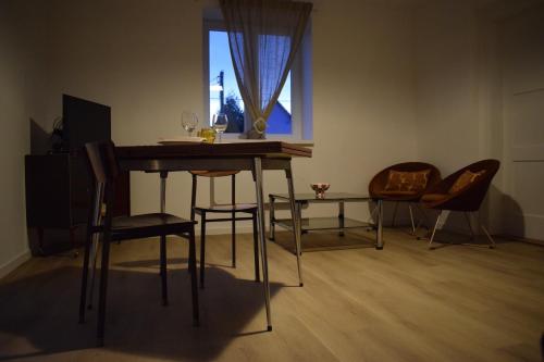 une pièce avec une table, des chaises et une fenêtre dans l'établissement Le 70s 2 pièces proche Colmar, à Holtzwihr